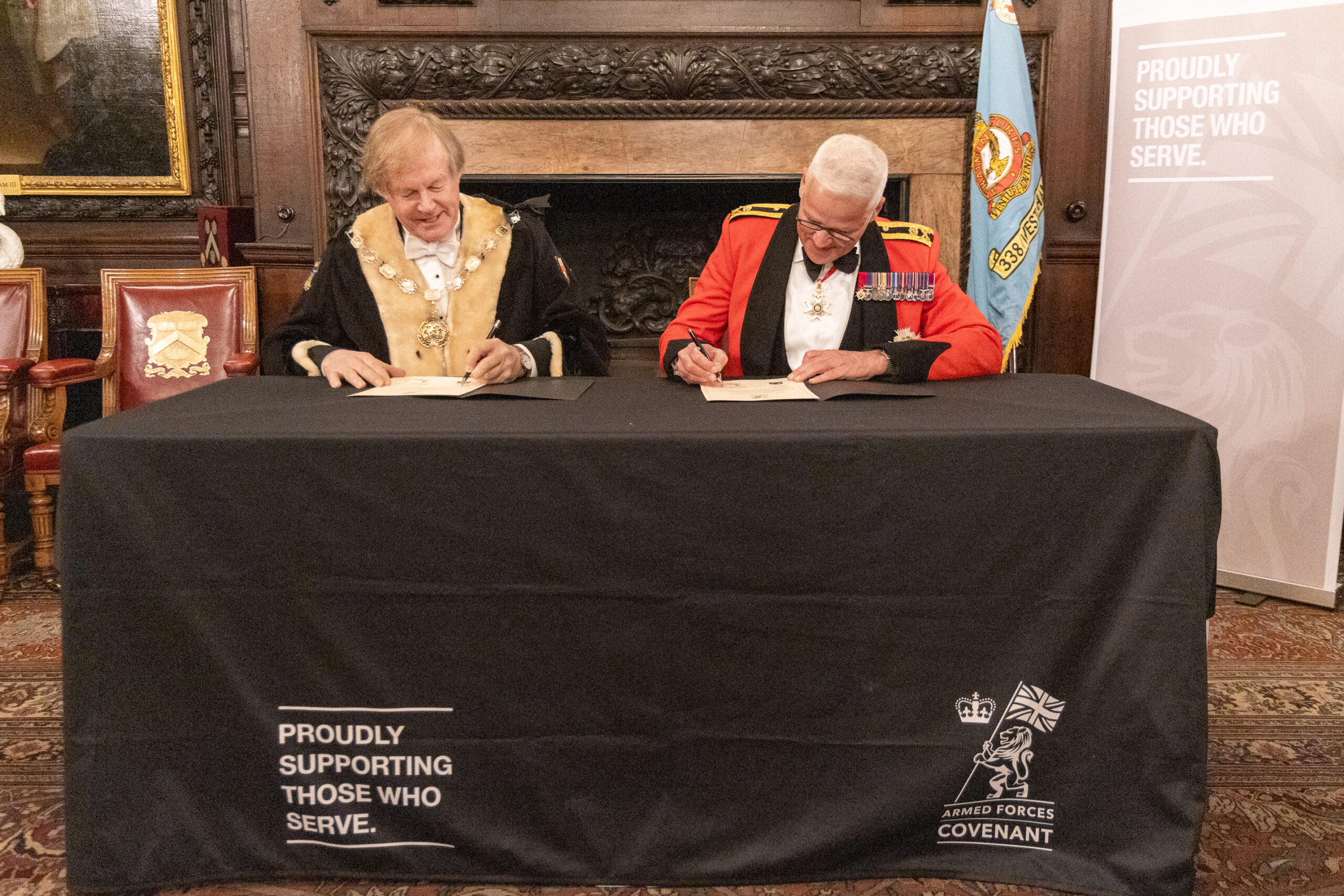 Photograph of 2 person signing the covenant behind desk